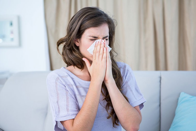 Woman sneezing into a tissue because of her allergies.