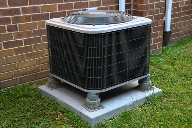 An A/C unit outside on the side of a house.