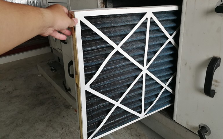 Hand replacing HVAC air filter