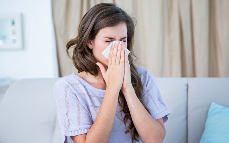 Woman sneezing into a tissue because of her allergies.