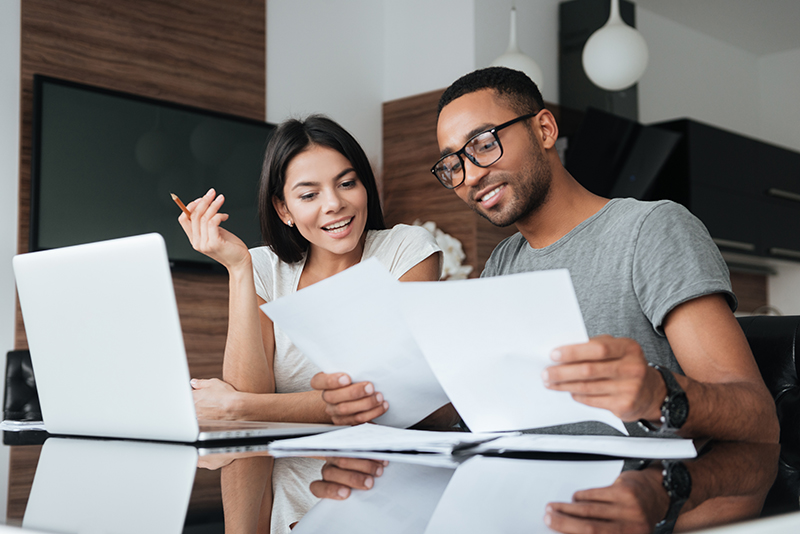 Couple sitting at table looking at financing options print out.