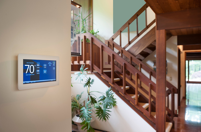 Smart thermostat on a wall next to stairs.